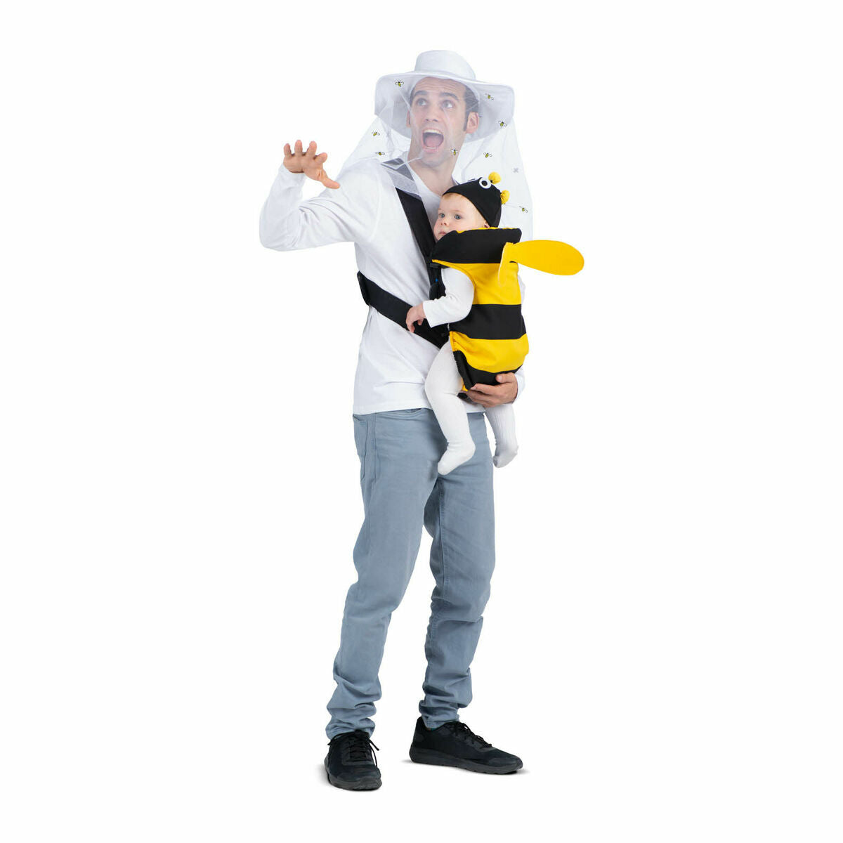 En man i vit tröja och ljusblå jeans bär en biodlarhatt med slöja och ser chockad ut, samtidigt som han bär en bebis i en gul och svart bi-dräkt i en bärsele framför sig.