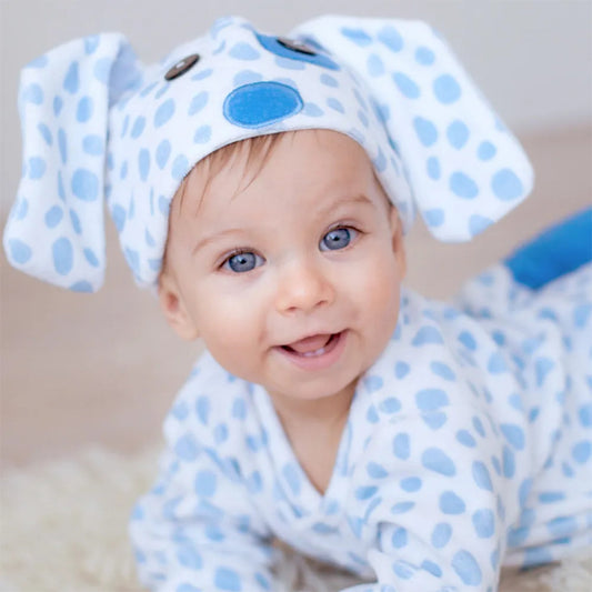 Närbild på en leende bebis som bär en prickig blå och vit hunddräkt med stora tygöron och blå nos.