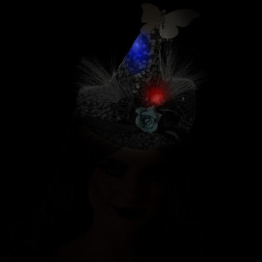 En glittrande mini-häxhatt som lyser i mörkret med en blinkande röd och blå LED-lampa, vilket skapar en magisk effekt.