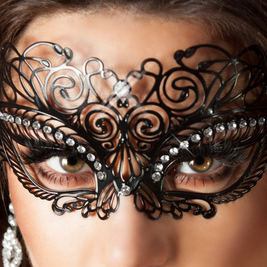 Närbild på en intrikat svart filigranmask i metall, dekorerad med gnistrande kristaller runt ögonen.