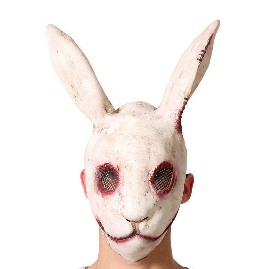 En person bär en Fasansfull Mördarskanin Mask i latex, med ett smutsigt, vitt ansikte, blodiga ögon och ett ihopsytt leende.