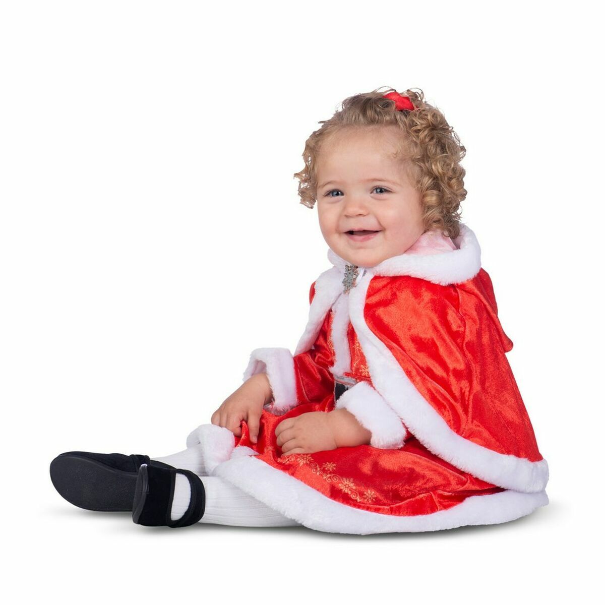 En skrattande bebis sitter på golvet i den kompletta röda tomteklänningen med cape.