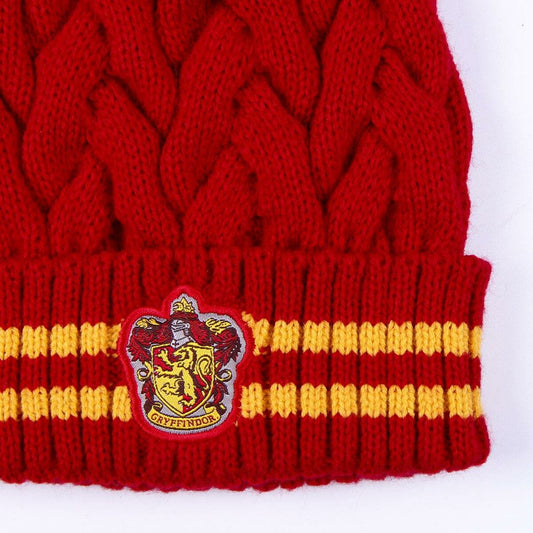 En närbild på det detaljerade, broderade Gryffindor-emblemet på den röda och gula mössan.