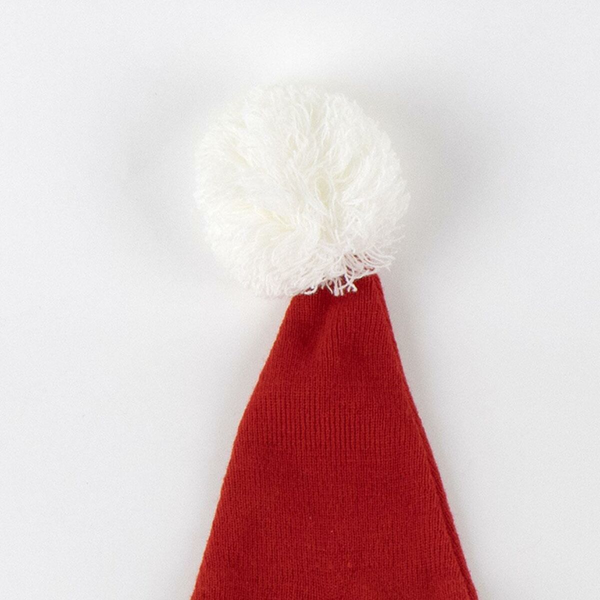 Närbild på den vita, fluffiga tofsen på toppen av en röd Grinchen tomtemössa.