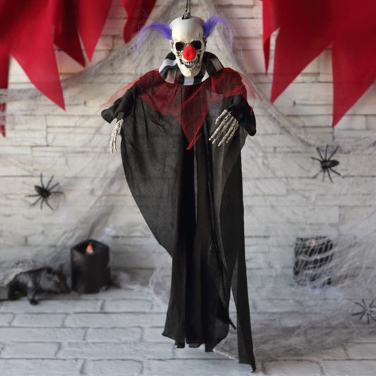 Den hängande skelett-clownen är upphängd mot en vit tegelvägg med spindelnät och andra Halloweendekorationer.