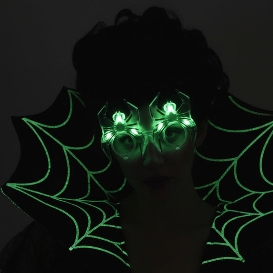 En kvinna bär de lysande spindelglasögonen som glöder med ett kusligt grönt sken i mörkret.