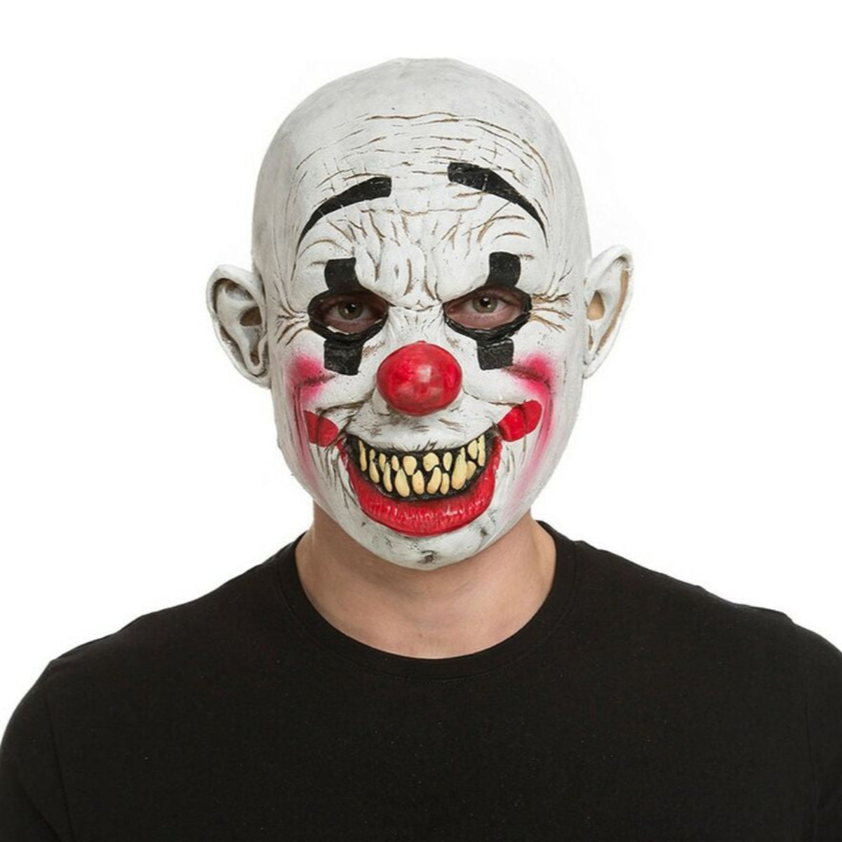 En person bär en skräckinjagande, heltäckande clownmask med ett sprucket vitt ansikte, en röd näsa och ett brett, demoniskt leende med vassa gula tänder.