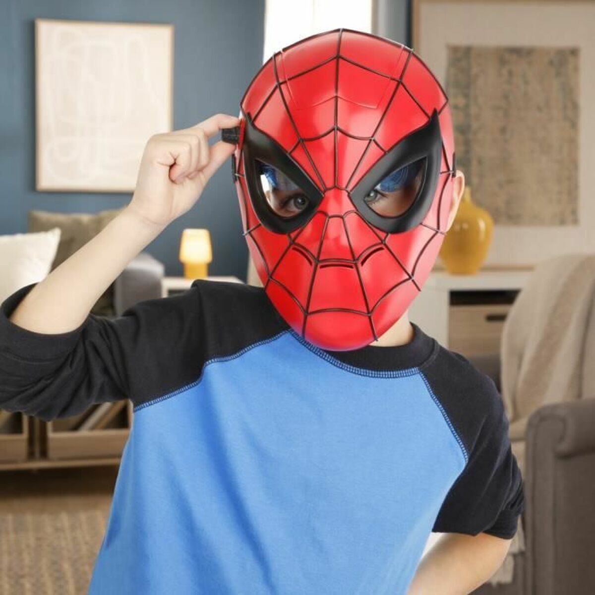 Ett barn bär Spider-Man-masken och trycker på knappen vid sidan för att aktivera de lysande ögonen.