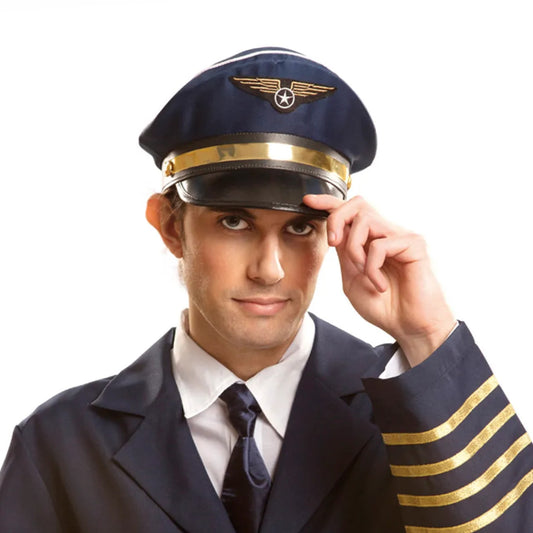 En man i en mörk pilotuniform med guldrevärer justerar sin stilrena, mörkblå flygkaptensmössa med en självsäker blick.