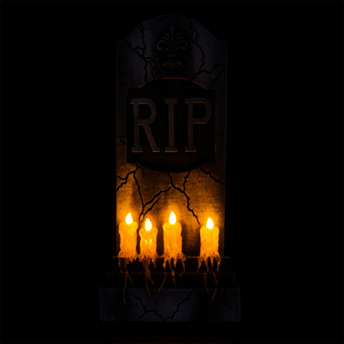 Den Storslagna R.I.P.-Gravstenen med de fyra ljusen som lyser med ett varmt, flimrande sken i totalt mörker.