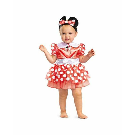En glad baby i en röd och vitprickig Minnie Mouse maskeraddräkt med puffärmar och ett matchande pannband med öron och rosett.