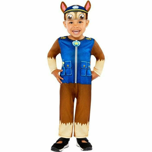 Ett glatt litet barn i en komplett maskeraddräkt som föreställer Chase från Paw Patrol, inklusive en blå uniformsväst och en hatt med hundöron.