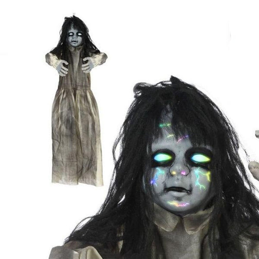 En närbild på en hängande Halloween-dekoration föreställande ett spöke eller en kuslig flicka med långt svart hår, grå hy och ögon som lyser starkt blågrönt, med små färgglada ljusblixtar i ansiktet.