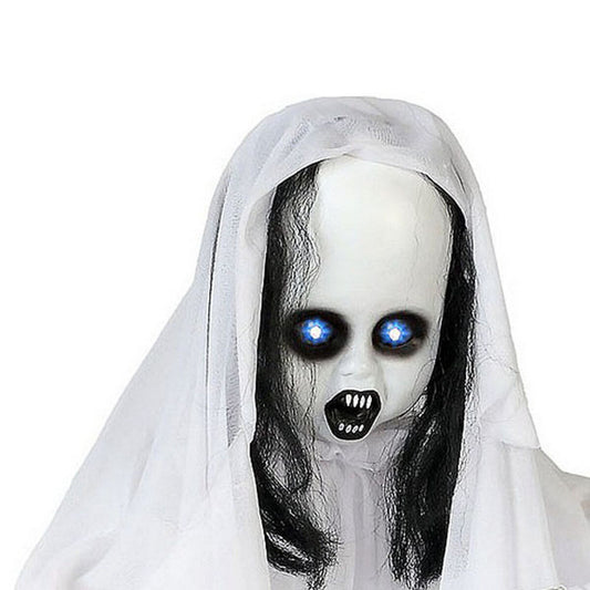 Närbild på en skräckinjagande hängande dekoration i form av en blek figur med långt svart hår, ett vitt slöjliknande tyg och lysande blå ögon samt en gapande mun med vassa tänder.