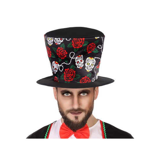 En vuxen man med skägg och mörk ögonmakeup bär en svart hög hatt dekorerad med färgglada mexikanska dödskallar (calaveras) och röda rosor.