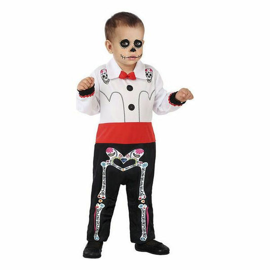 En liten pojke klädd i en färgglad maskeraddräkt föreställande ett Day of the Dead-skelett, med vit skjorta, röd midjeband och svarta byxor med blommiga skelettdetaljer.