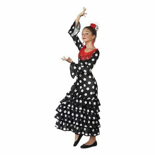 Ett barn i en svart flamenco-inspirerad maskeradklänning med vita prickar, röda detaljer och vida ärmar, i en dansande pose.