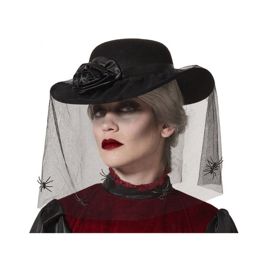 En kvinna bär en elegant svart hatt med en stor svart ros och en svart nätslöja dekorerad med små spindlar som täcker delar av hennes ansikte.