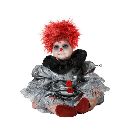 En bebis sitter i en grå, blodig clowndräkt med röd, spretig peruk och röda clownskor.