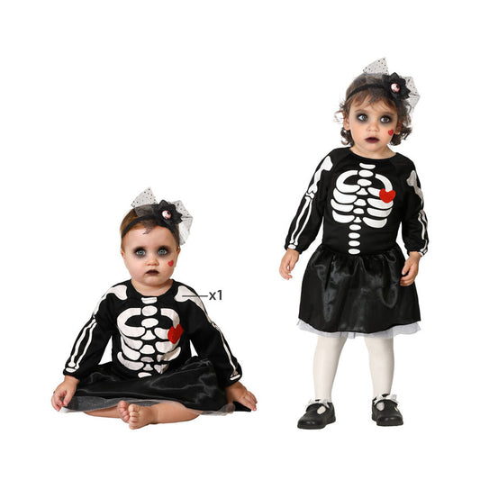 Två bilder på en baby/småbarn som bär en svart skelettmaskeraddräkt med vitt tryck och ett rött hjärta på bröstet, samt ett svart diadem med tyll.