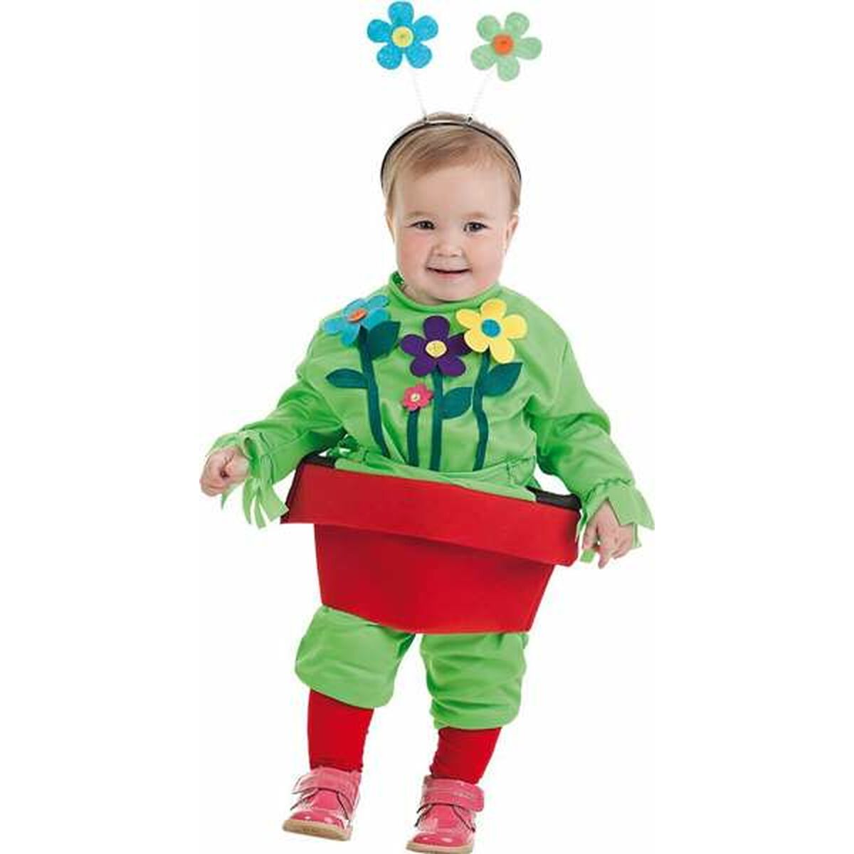 En glad bebis klädd i en grön dräkt som ser ut som en växt som kommer upp ur en stor röd blomkruka, komplett med en blomster-diadem.