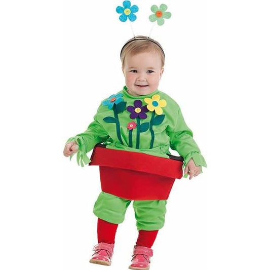 En glad bebis klädd i en grön dräkt som ser ut som en växt som kommer upp ur en stor röd blomkruka, komplett med en blomster-diadem.