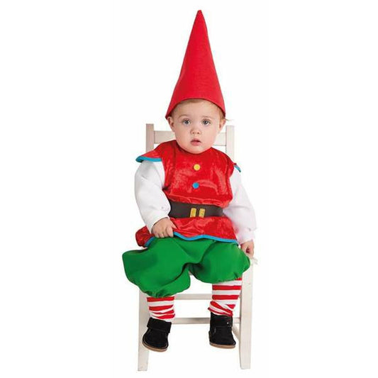 En söt bebis klädd i en röd och grön gnomdräkt med en hög röd mössa, sittandes på en vit stol.