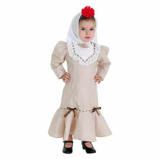 En liten flicka i en beige Chulapa maskeraddräkt med lång kjol, vita spetsdetaljer vid kragen, och en vit huvudduk med en röd boll på toppen.