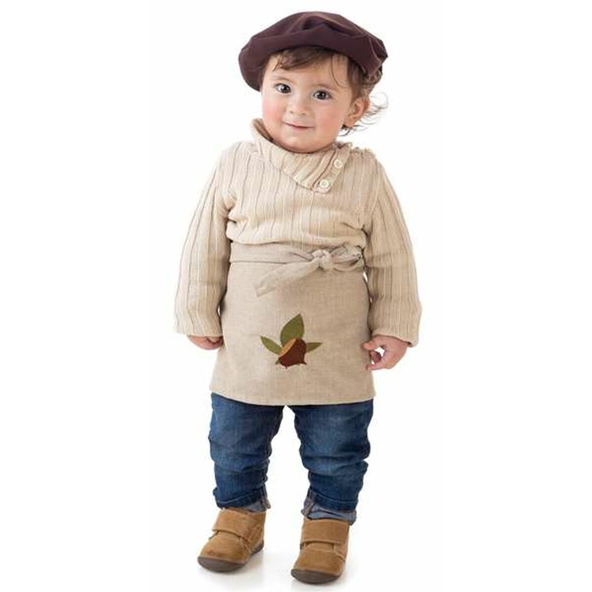 En bebis i en söt kastanjedräkt med ett beige förkläde och en kastanjedesign.