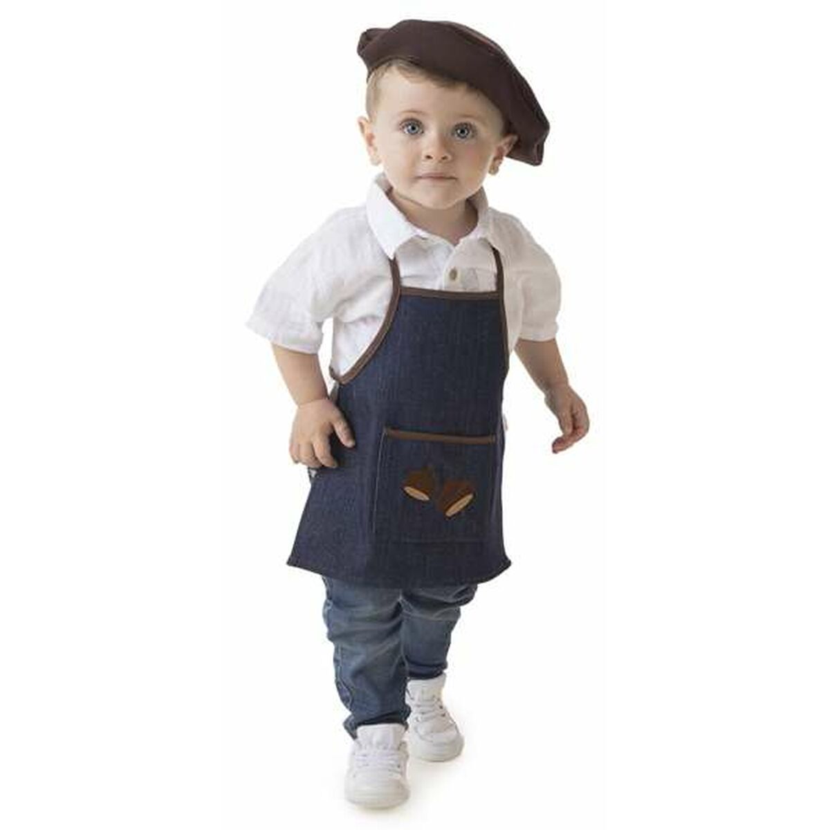 En liten bebis eller ett mycket ungt barn med blå ögon bär ett mörkblått förkläde med kastanjedetaljer och en brun basker.
