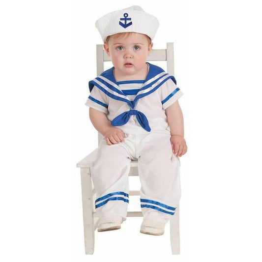 En liten bebis sitter på en vit stol klädd i en vit och blå sjömansdräkt, komplett med en vit mössa med ett blått ankare på.