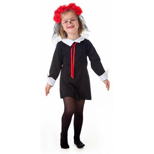 Ett leende litet barn klädd i en svart Catrina-inspirerad maskeraddräkt med vit krage, röda band i halsen och en stor röd blomsterkrans med svart slöja.