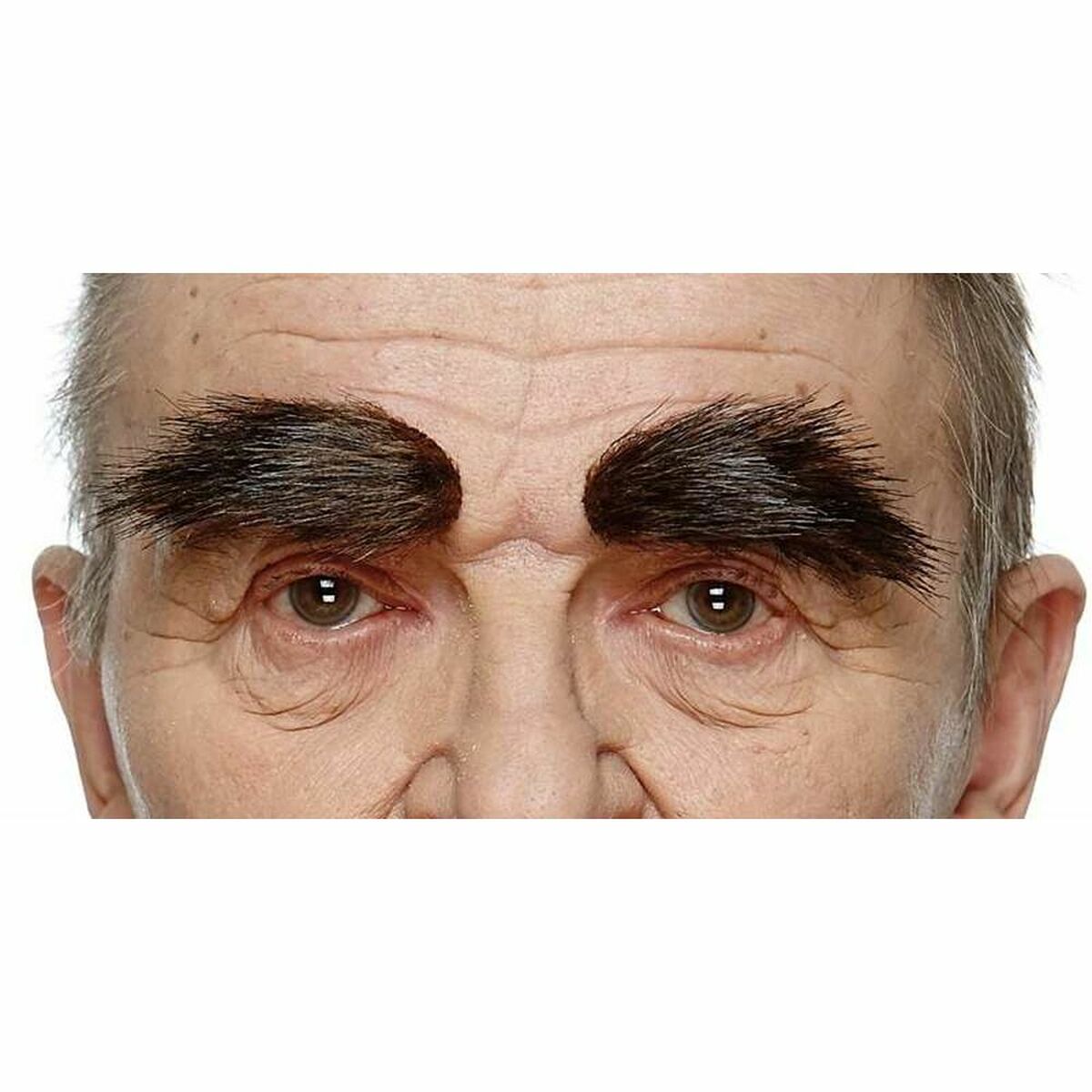 En närbild på en äldre persons ansikte som bär extremt stora, buskiga svarta fejkögonbryn som täcker större delen av pannan ovanför ögonen.