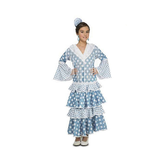 En ung flicka poserar i en långärmad, blå och vit prickig flamenco-maskeraddräkt med vita fransar vid halsen och volanger på kjolen.
