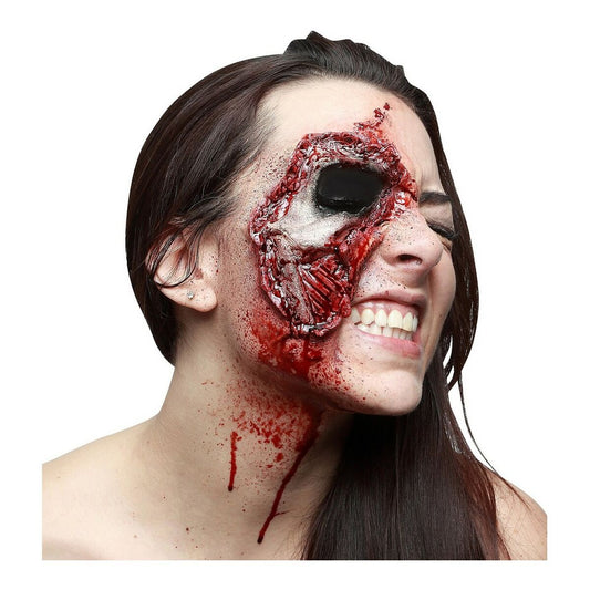En kvinna visar upp en realistisk latex-zombie-skada som täcker halva hennes ansikte, med synliga sårvävnader och blodstänk på halsen.