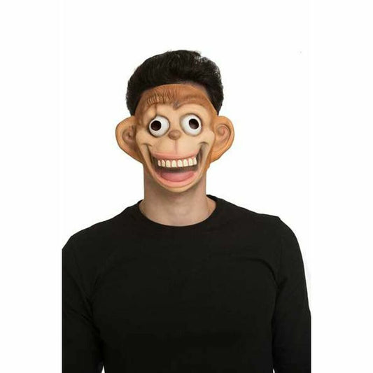 En man bär en överdimensionerad, brun apa-mask med stora vita ögon och ett extremt brett, tandfyllt leende, mot vit bakgrund.