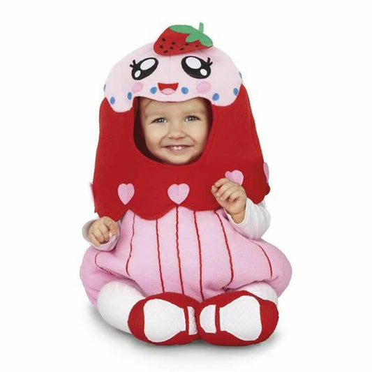 Ett leende litet barn sitter klätt i en mjuk, rosa och röd cupcake-maskeraddräkt med en jordgubbe på hatten.