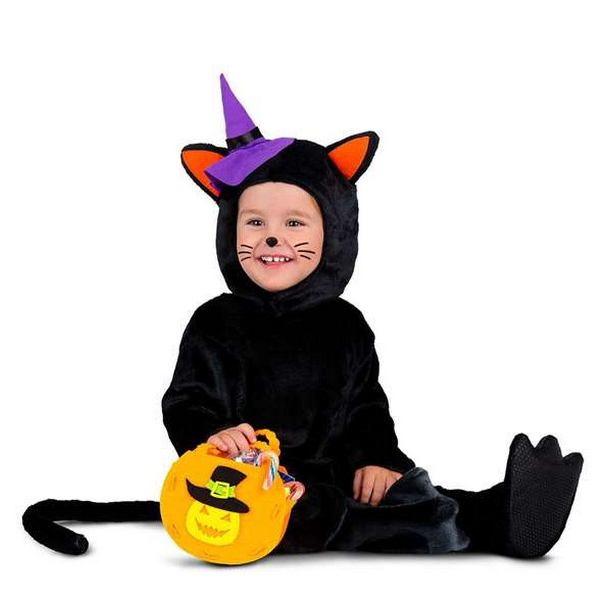 Ett litet barn sitter i en mjuk, svart dräkt som föreställer en katt med öron och svans, bärandes en liten lila häxhatt. Barnet ler och håller en orange pumpaformad godispåse.