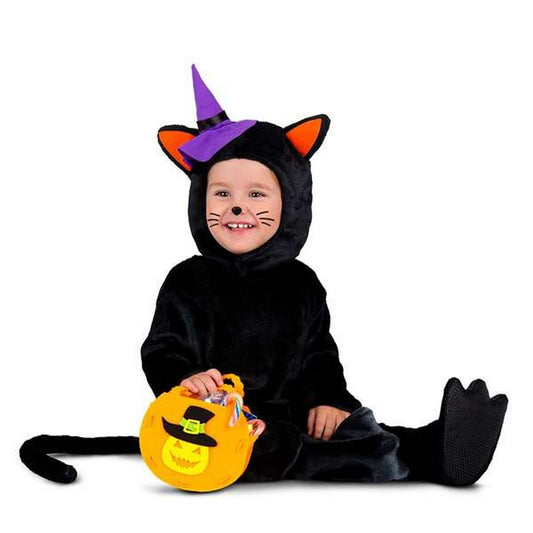 Ett litet barn sitter i en mjuk, svart dräkt som föreställer en katt med öron och svans, bärandes en liten lila häxhatt. Barnet ler och håller en orange pumpaformad godispåse.