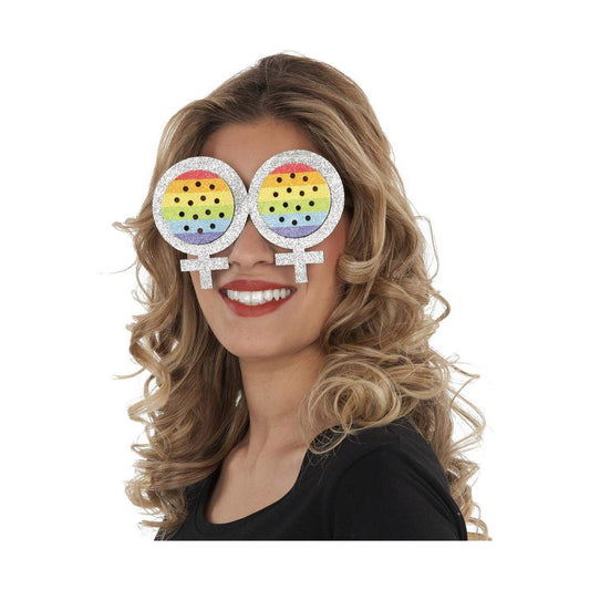 En kvinna ler och bär ett par stora, glittriga festglasögon formade som två sammanlänkade kvinnliga köns-/venus-symboler med regnbågsfärgad insida och perforerade hål för ögonen.