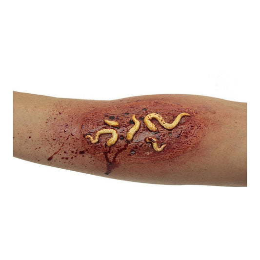Närbild på en arm där en realistisk skada med blod och flera krypande, gula larver gjorda av latex applicerats på huden.