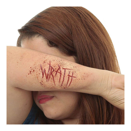 En kvinna täcker sitt ansikte med armen där en realistisk latex-tatuering visar texten "WRATH" omgiven av blodstänk.