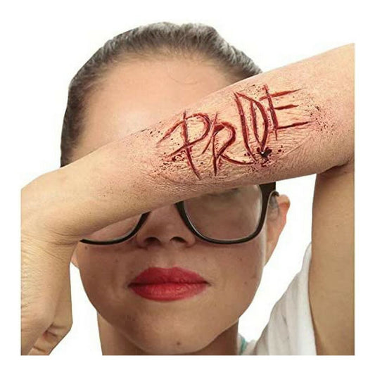 En person som täcker delar av sitt ansikte med sin arm, där en realistisk latexapplikation som ser ut som ordet 'PRIDE' inristat med djupa sår och blodstänk sitter på underarmen.
