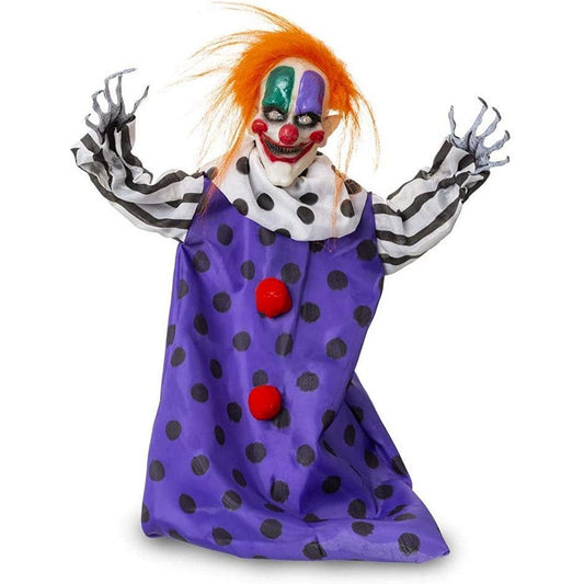 En hängande, skräckinjagande clownfigur med vilt orange hår, vit och målad mask, randiga ärmar och en lila klänning med svarta prickar och röda pom-poms.