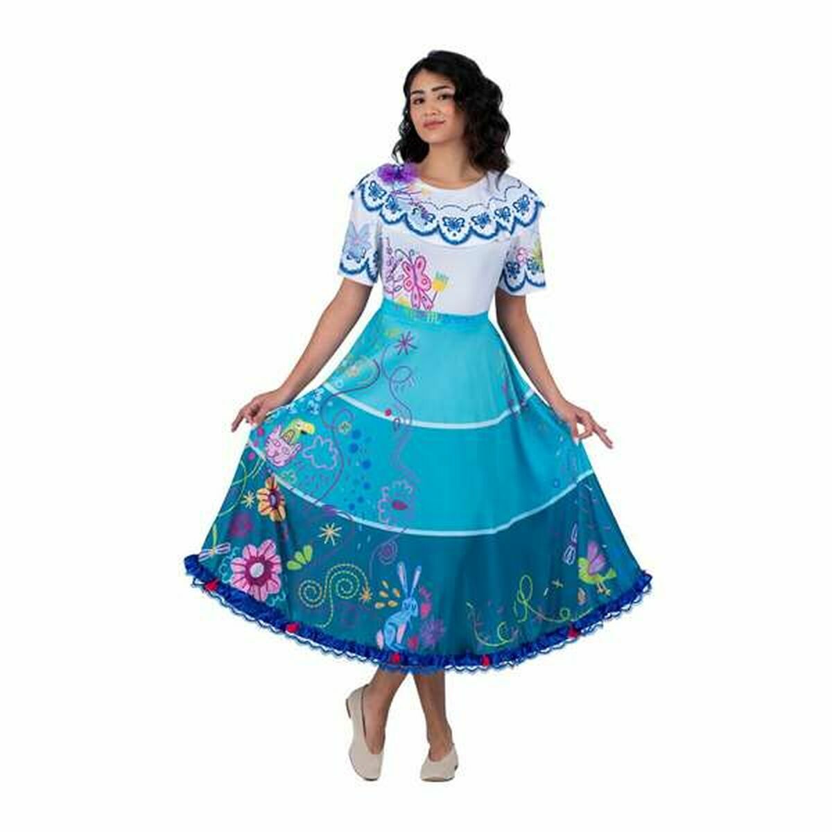 En kvinna poserar i en färgglad, knälång maskeraddräkt inspirerad av Colombia, med vit blusdel med volangkrage och en blå, mönstrad kjol med blommor och djurmotiv.