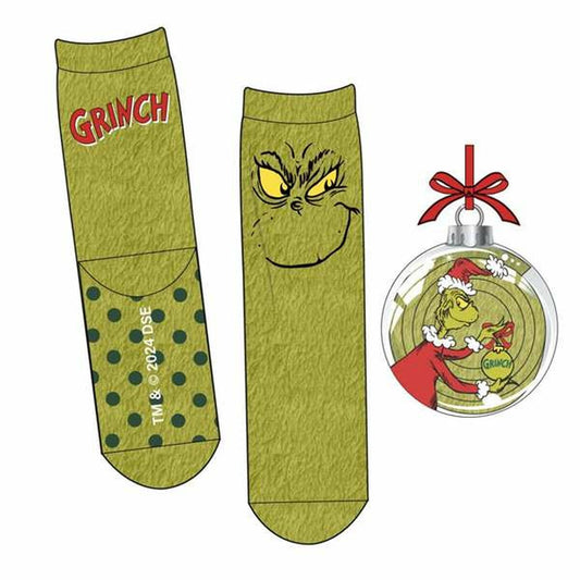 Ett par grönmelerade julstrumpor med Grinch-tema. Den ena strumpan har texten 'GRINCH' och prickar, den andra har ett stort, illasinnat Grinch-flin. En genomskinlig julgranskula med Grinch i tomtedräkt medföljer som tillbehör.
