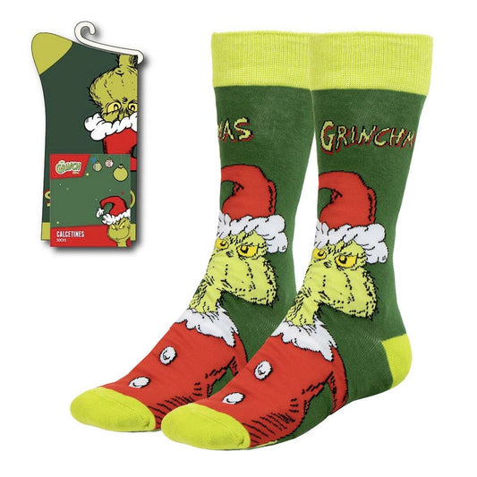 Ett par gröna och röda julstrumpor med motiv av den griniga karaktären Grinchen utdragna ur sin förpackning.