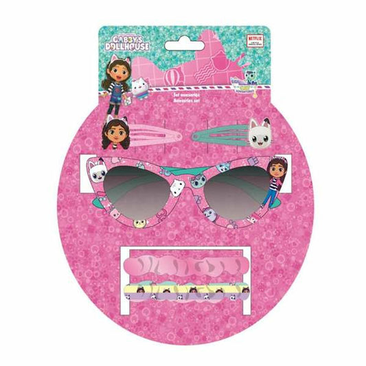 Ett set med barnaccessoarer från Gabby's Dollhouse på en rosa, prickig förpackning. Setet innehåller ett par rosa solglasögon dekorerade med karaktärer, två hårklämmor och ett paket med hårsnoddar.