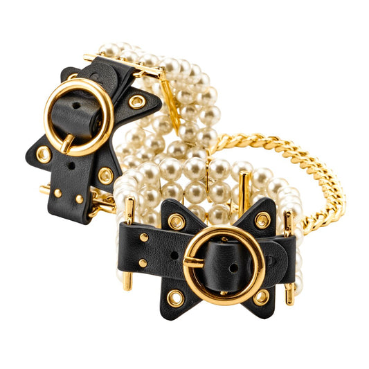 Ett par svarta bojor med tjocka rader av vita pärlor, svarta läderdetaljer med guldfärgade spännen, sammanlänkade med en guldfärgad kedja.