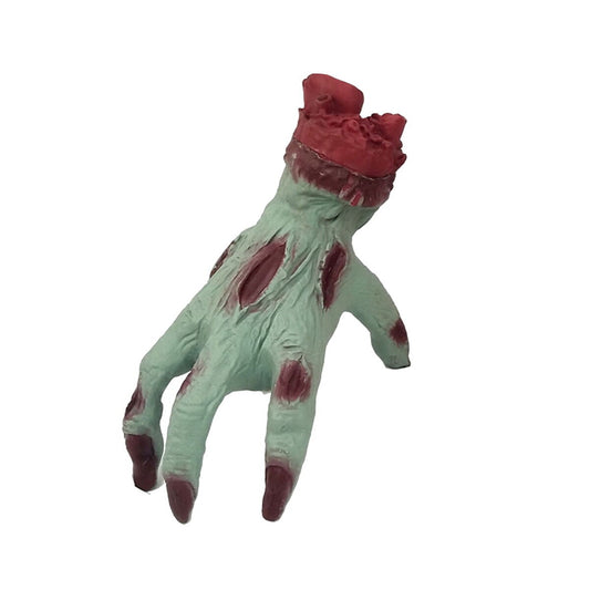 En avhuggen, grönaktig zombiehand med synliga röda sår och en stumpig, blodig topp.